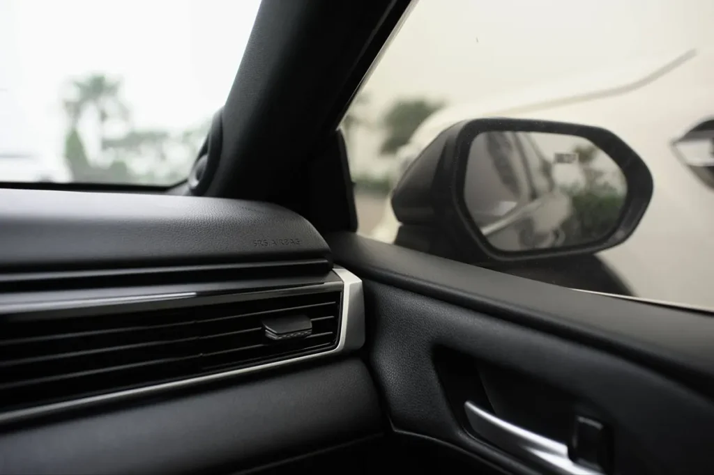 WOW Wipes® 6 Unexpected Places Where Wet Wipes Save Time A sleek car interior with focus on side mirror reflecting another car.